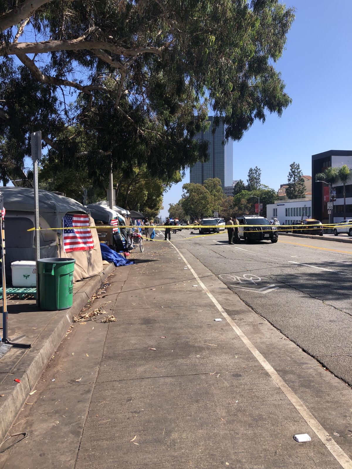Yellow police tape surrounds part of a homeless encampment