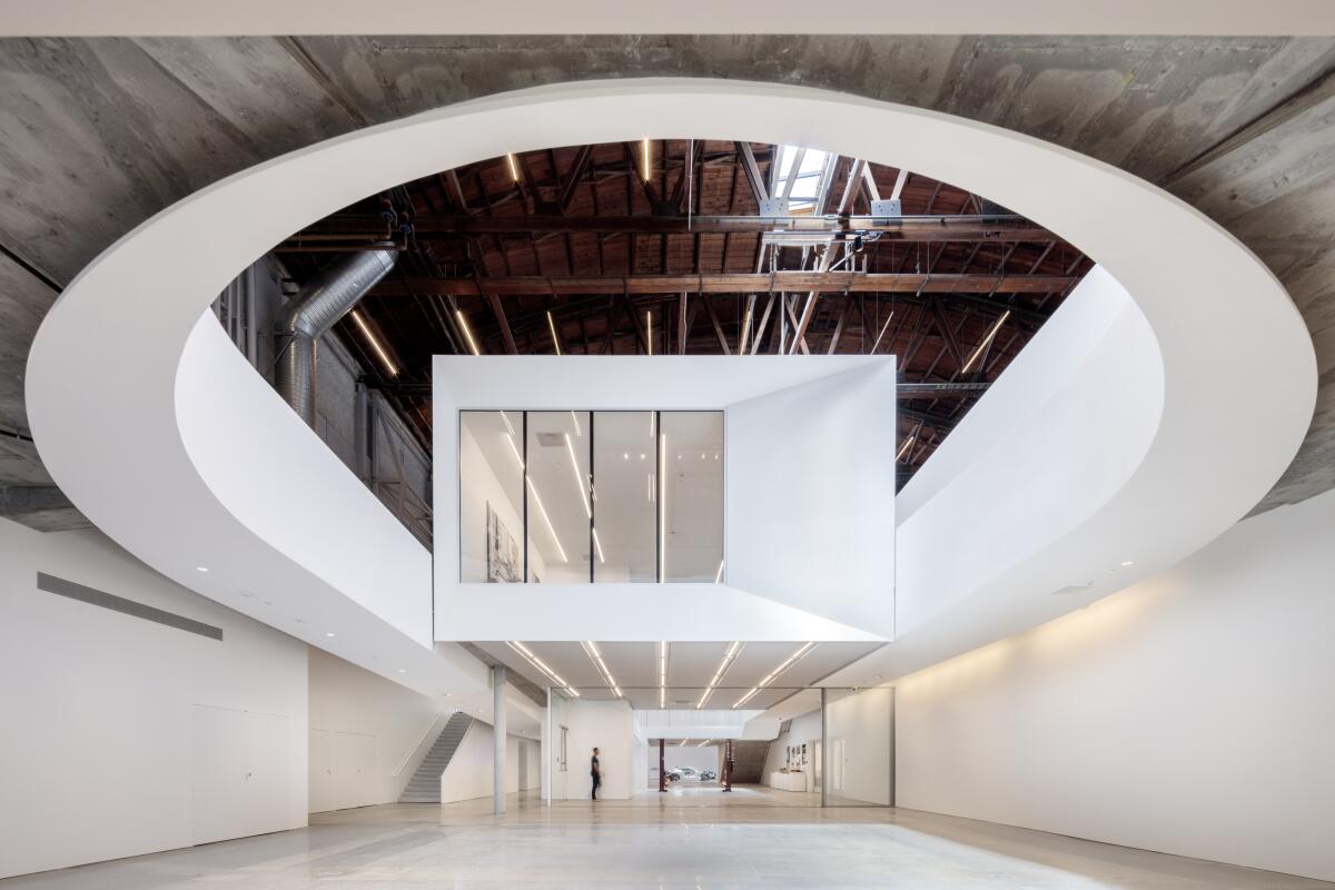 Inside a warehouse, a boxy second-floor room appears suspended midair, flanked by dramatic curved ramps. 