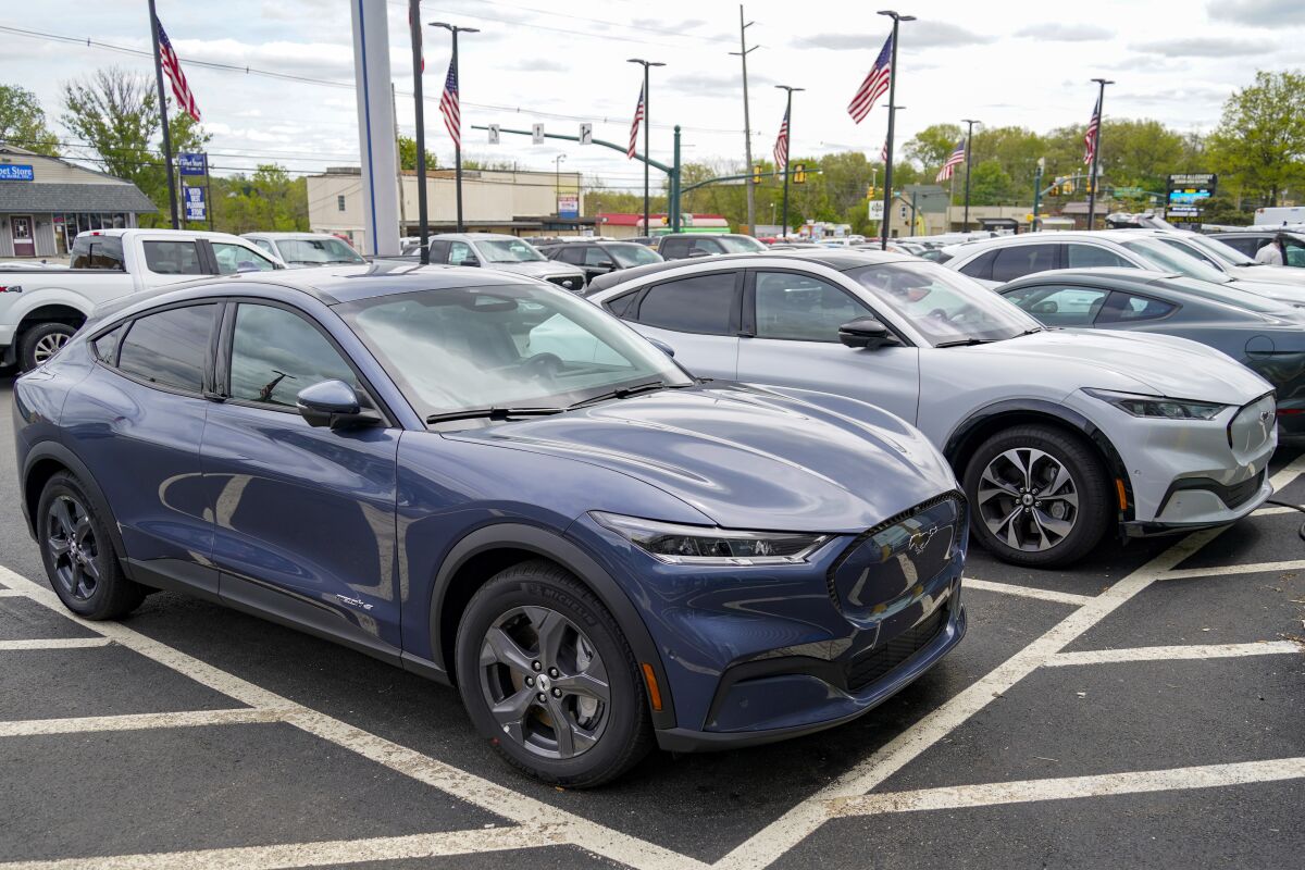 FILE - A pair of 2021 Ford Mustang Mach E are displayed for sale at a Ford dealer on Thursday, May 6, 2021, in Wexford, Pa. U.S. new vehicle sales rebounded slightly last year from 2020′s dismal numbers, but forecasters expect them to be more than 2 million below the years before the coronavirus pandemic. (AP Photo/Keith Srakocic, File)