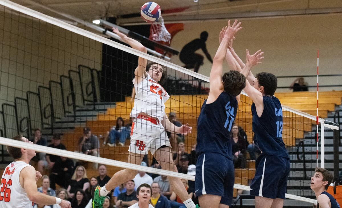 Huntington Beach's Nick Ganier hits against Corona del Mar's Sterling Foley (11) and Daniel Booker (12) on Tuesday.