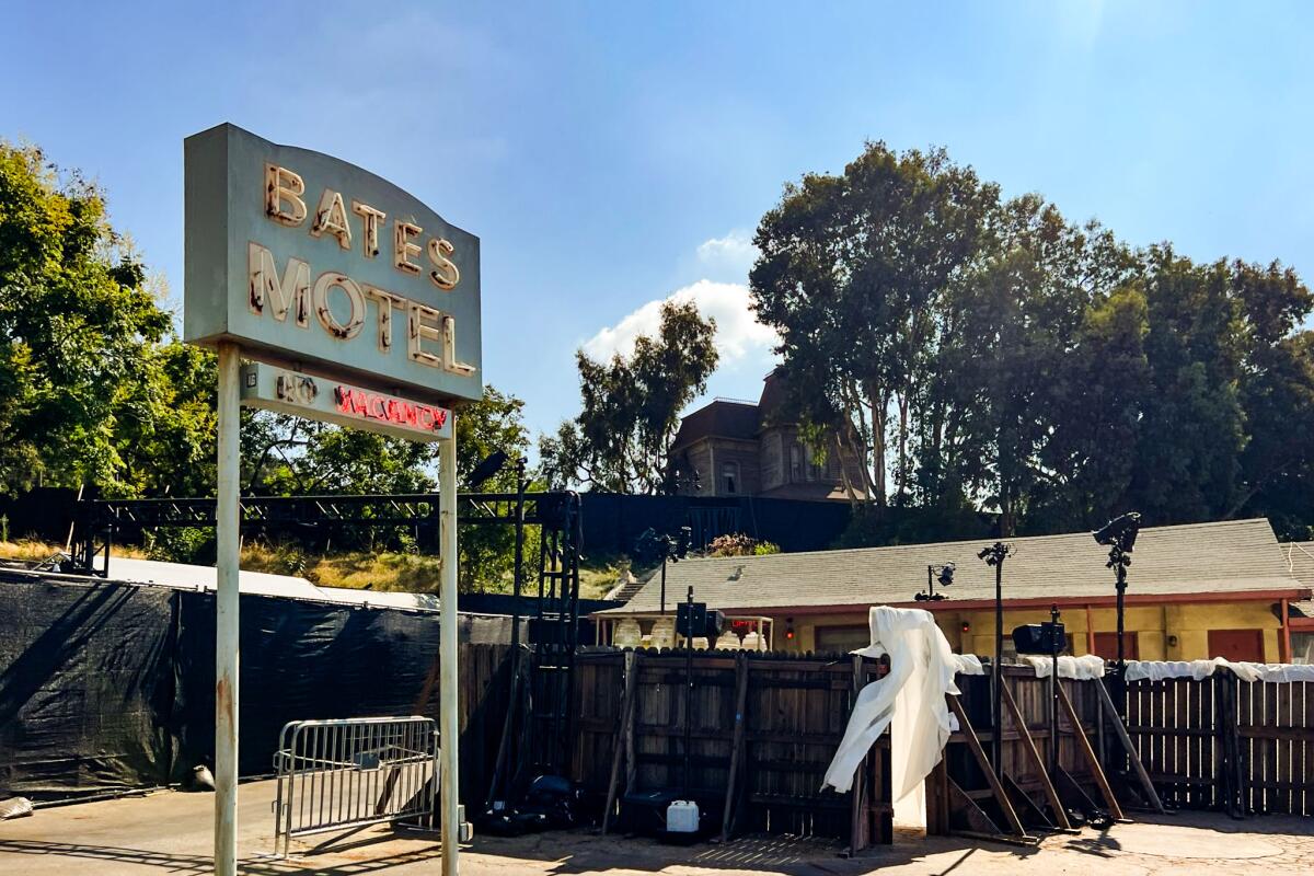 A sign that reads Bates Motel in the foreground, with a house on the hill in the background.