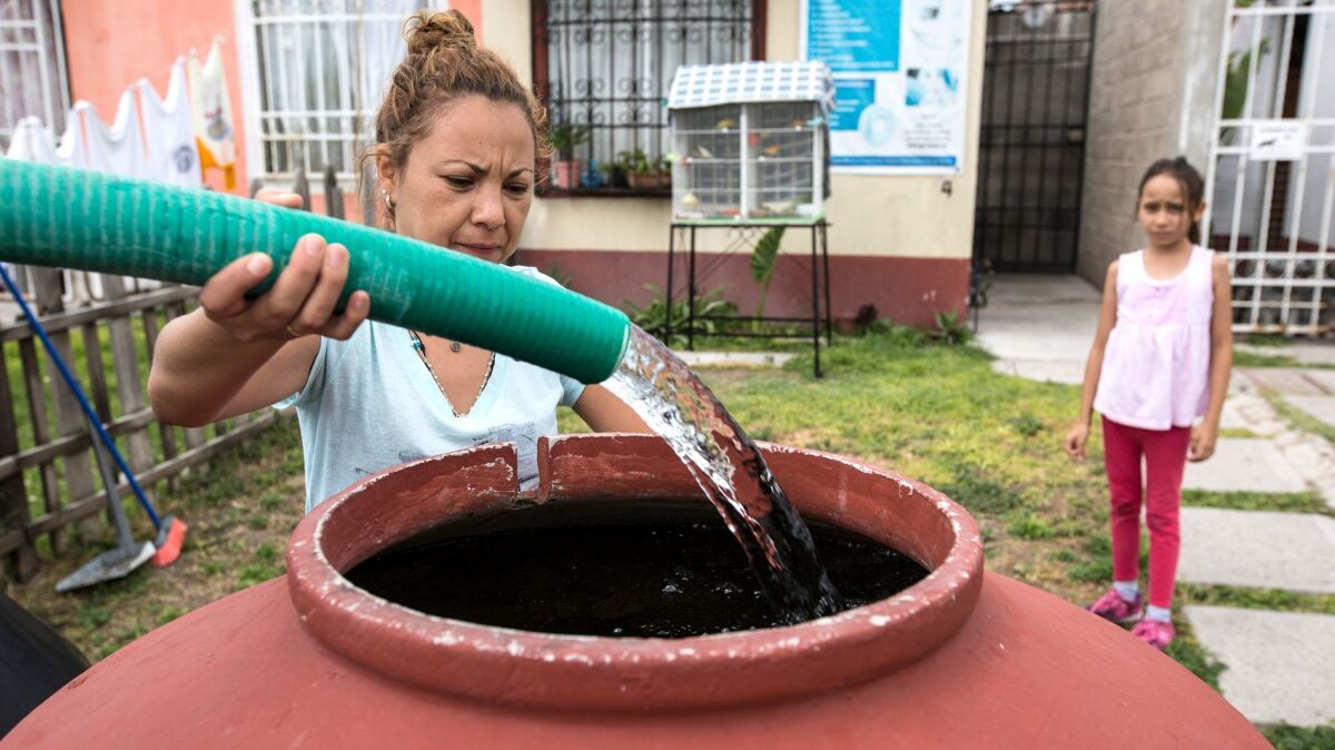 Anahid Figueroa, a resident of the Homex-built Santa Teresa development in Huehuetoca, Mexico, fills a barrel with water from a truck after the development's water system failed.