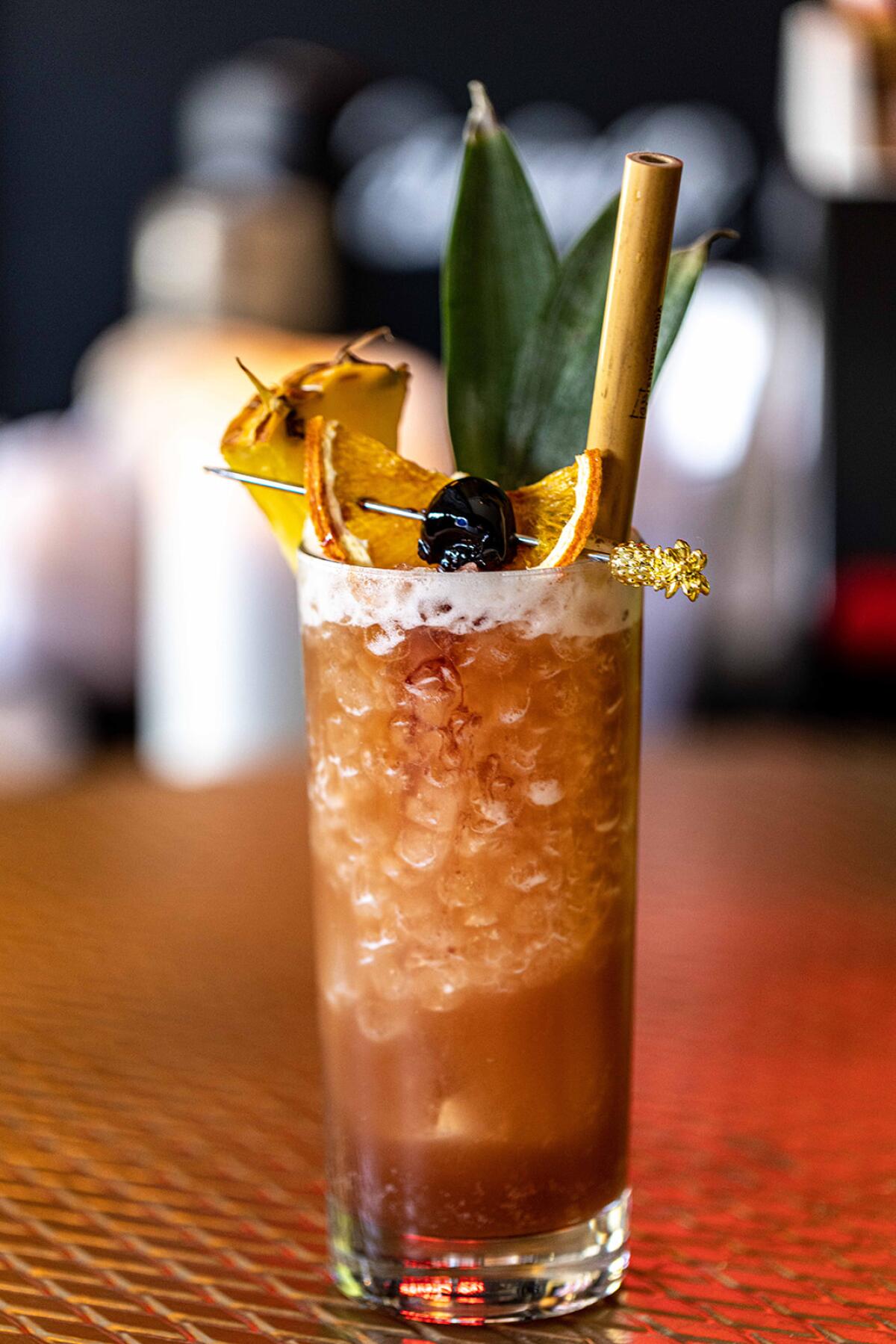 A vertical photo of a Royal Hawaiian tiki cocktail garnished with pineapple.