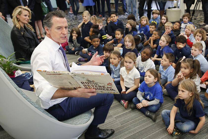 Gov. Gavin Newsom reads the book "Rosie Revere, Engineer by Andrea Beaty and David Roberts to kindergarteners at the Washington Elementary School in Sacramento, Calif., Friday, March 1, 2019. Newsom, accompanied by his wife, Jennifer Siebel Newsom, left, visited the school to celebrate Read Across America Day. (AP Photo/Rich Pedroncelli)