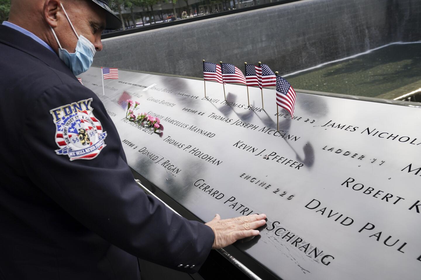 A New York Fire Department member brushes his fingers over the name of a victim at the National September 11 Memorial