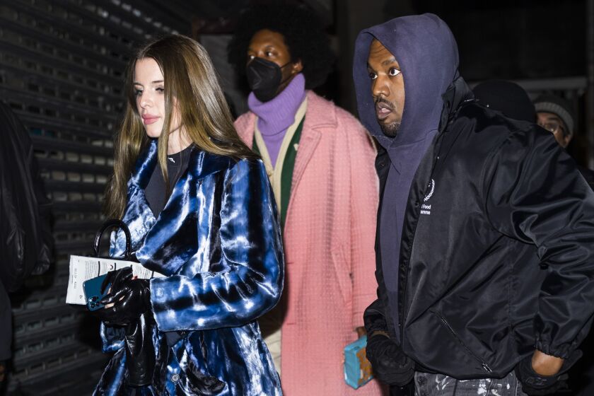 Julia Fox and Kanye West walk with a man behind them