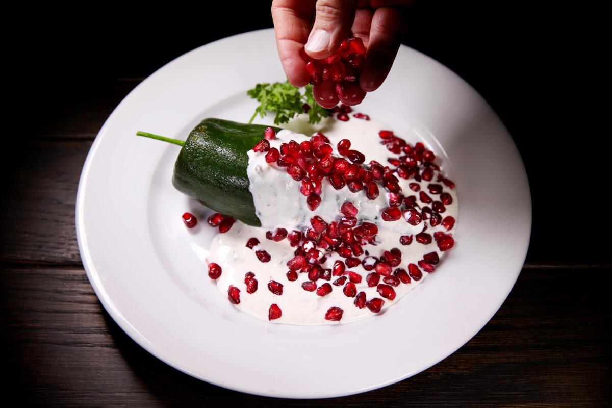 Chile en nogada: A poblano chile stuffed with ground pork, dried fruit, walnuts and candied cactus, and topped with pecan cream sauce and pomegranate.