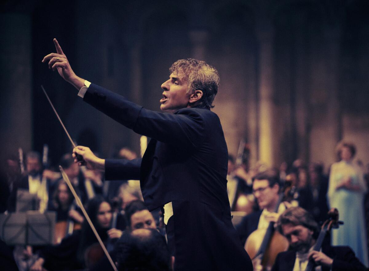 A man conducts an orchestra inside a cathedral.
