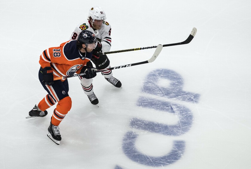 Edmonton Oilers' James Neal (18) and Chicago Blackhawks' Drake Caggiula (91) battle for the puck during the second period of an NHL Stanley Cup playoff hockey game in Edmonton, Alberta, Saturday, Aug. 1, 2020. (Jason Franson/The Canadian Press via AP)