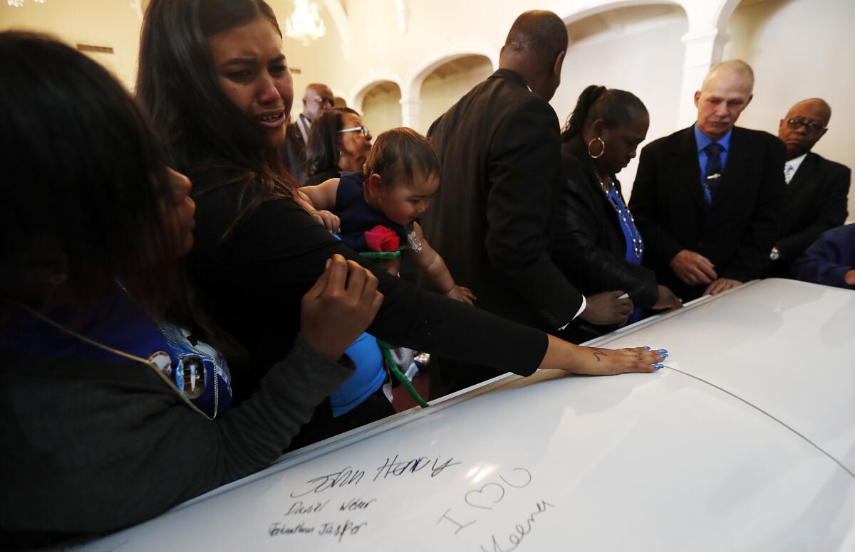 Violet Weber, the infant daughter of Anthony Weber, reaches for the casket during funeral services in Inglewood. After the Weber family filed a civil rights lawsuit, the Sheriff’s Department said it will “remain silent” as it continues to investigate the shooting.