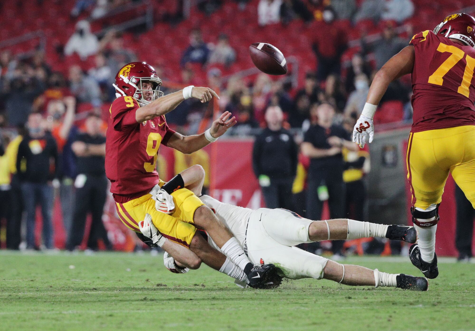 USC quarterback Kedon Slovis throws as he's pulled down by Oregon State linebacker Riley Sharp.