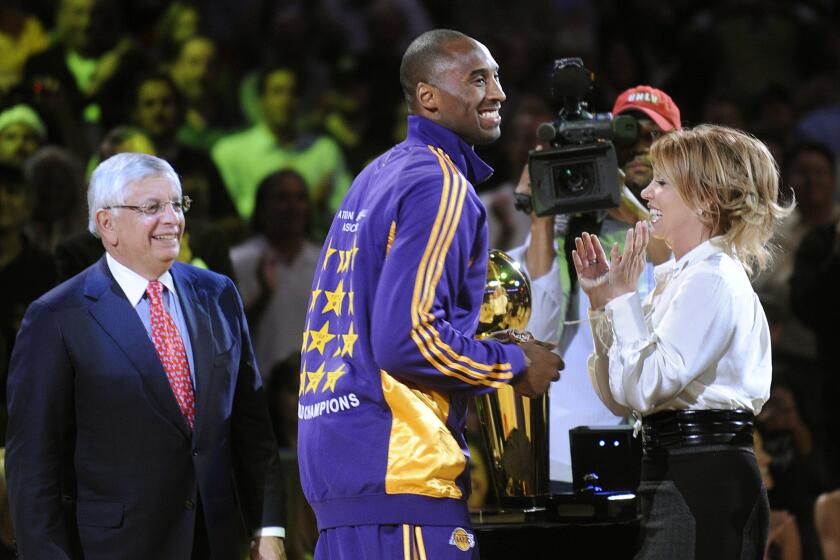 Kobe Bryant smiles after receiving his championship ring from NBA commisioner David Stern, left, and Jeanie Buss on Oct. 27, 2009, at Staples Center.