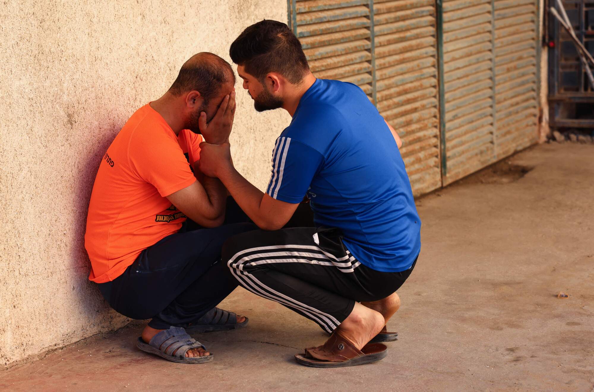 One man comforts another on the street. 