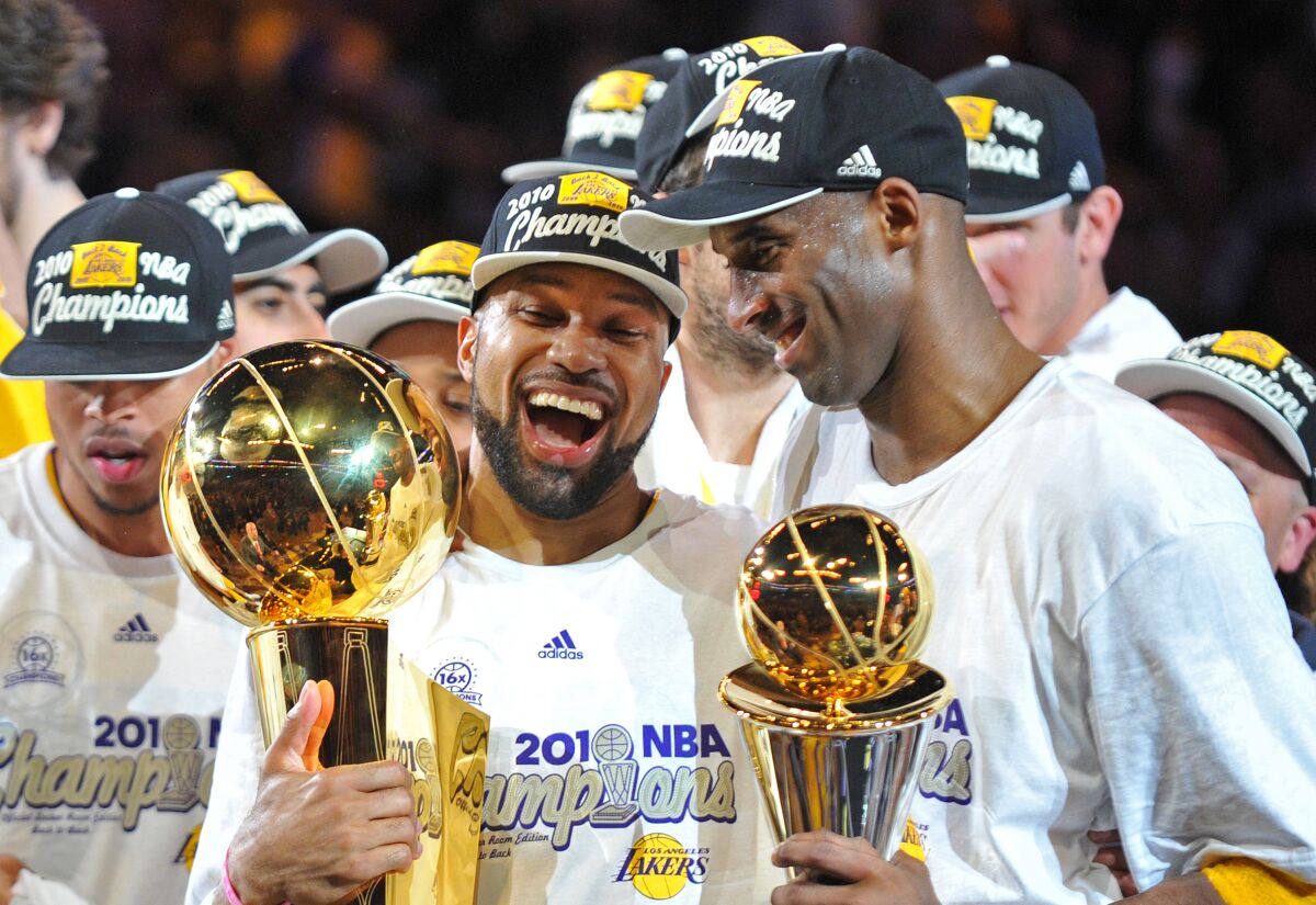 Los AngeLakers Derek Fisher and MVP Kobe Bryant hold the team and MVP trophies.