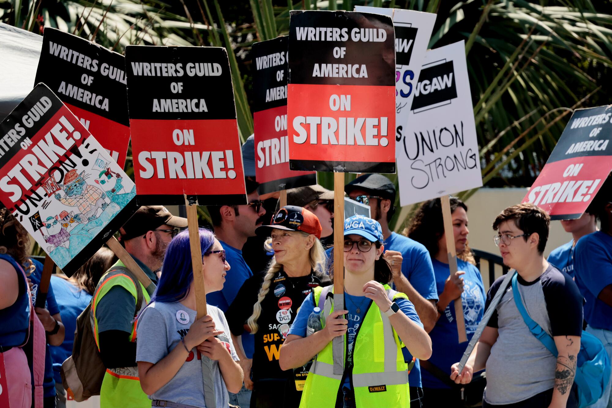 Workers holding picket signs that read "Writers Guild of America on Strike" and "Union Strong."
