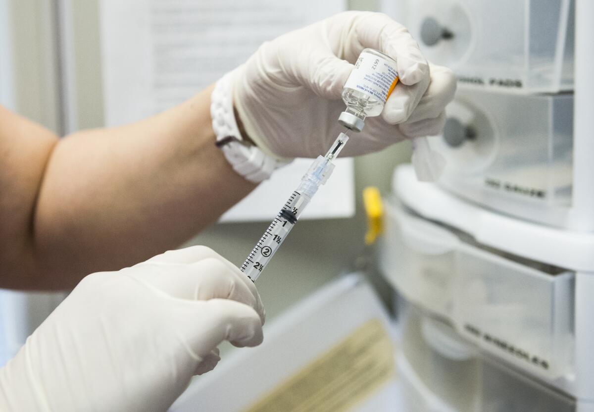 A flu vaccine is drawn from a vial.