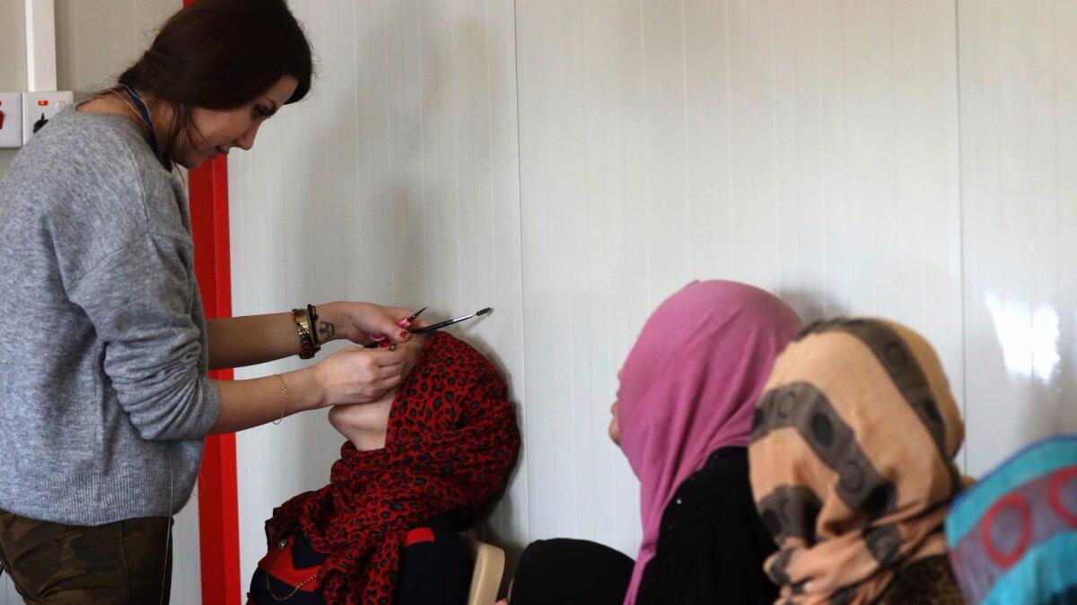 A displaced Iraqi woman, who fled the violence in the northern city of Mosul as a result of a planned operation to retake the city from jihadists, has her eyebrows plucked at a makeshift beauty salon at the Hasan Sham camp on Jan. 18 in the village of Hasan Sham, east of Irbil.