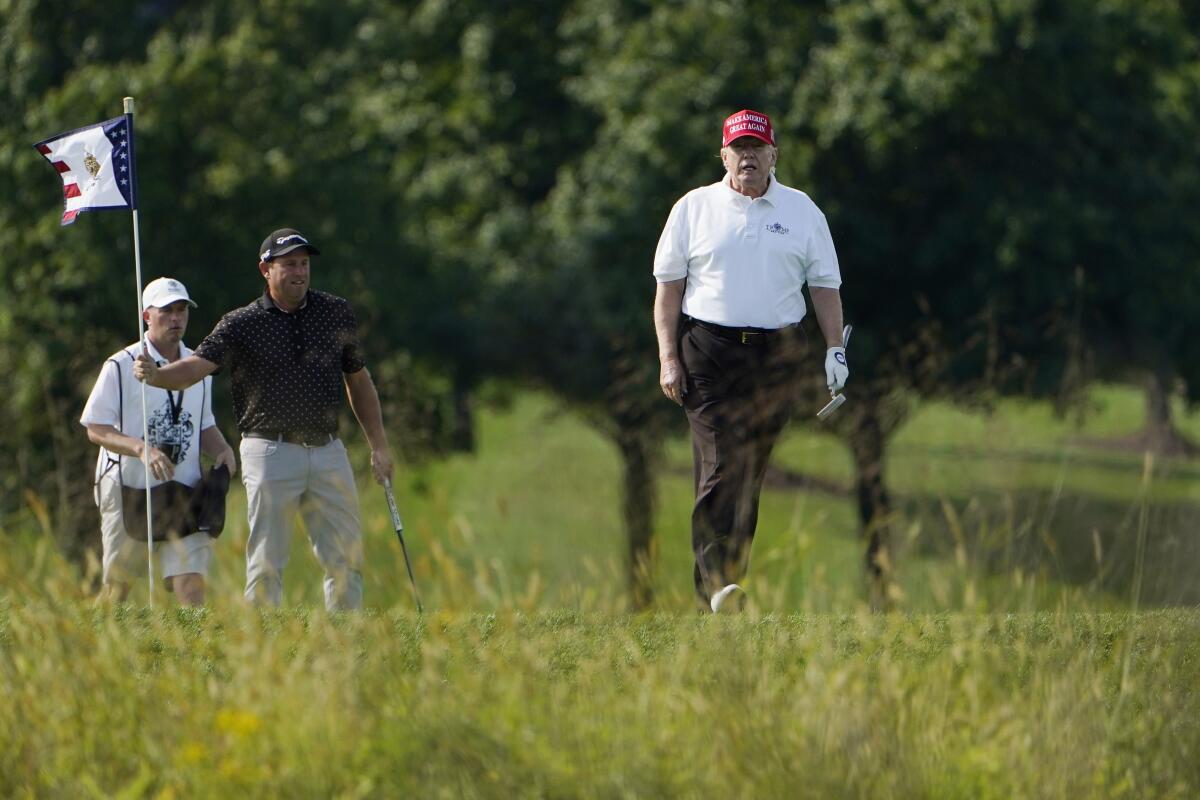 Former President Trump walks on a golf course.