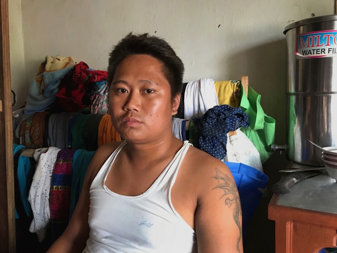 A Nepali man in a white tank top inside his home