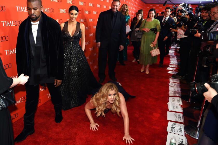 Comedian Amy Schumer pretends to trip and fall on the floor in front of honorees Kim Kardashian and Kanye West at the Time 100 Gala at Lincoln Center on Tuesday in New York.