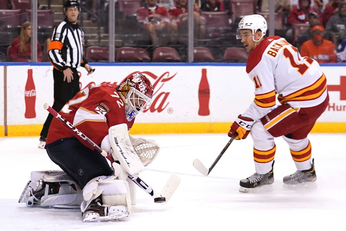 Florida Panthers goaltender Sergei Bobrovsky (72) stops the puck as Calgary Flames center Mikael Backlund (11) looks on during the second period of an NHL hockey game, Tuesday, Jan. 4, 2022, in Sunrise, Fla. (AP Photo/Lynne Sladky)