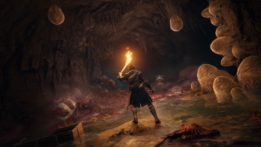 In a still image from a video game, a helmeted, kilted figure holds a torch.