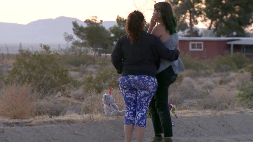 Two people gather near the site of a hit-and-run crash that killed three girls.