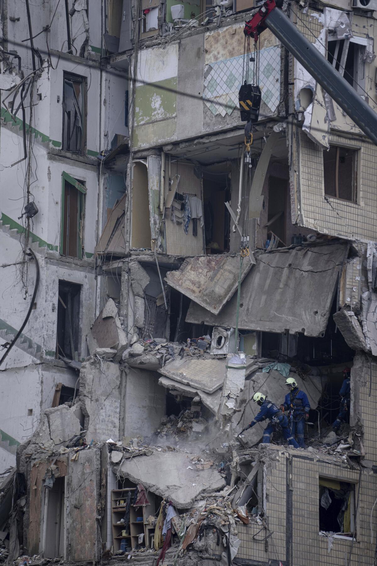 Two workers stand in a destroyed apartment building.