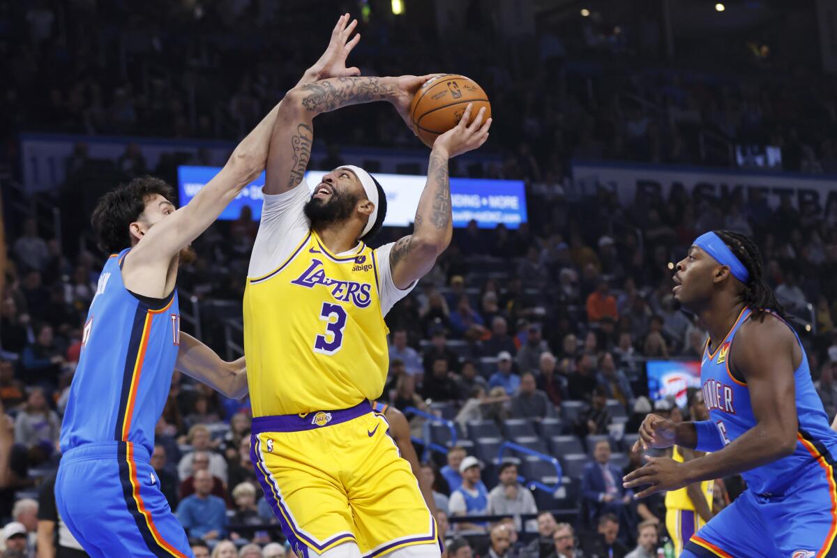 Lakers forward Anthony Davis tries to shoot while Thunder forward Chet Holmgren, left, plays tight defense.