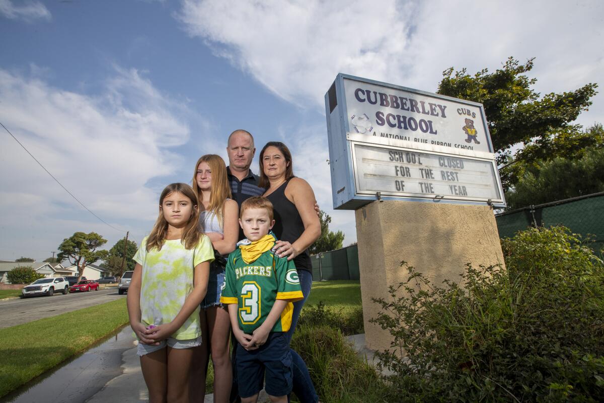 A family stands together for a portrait in front of a Cubberley School sign that says closed for the rest of the year
