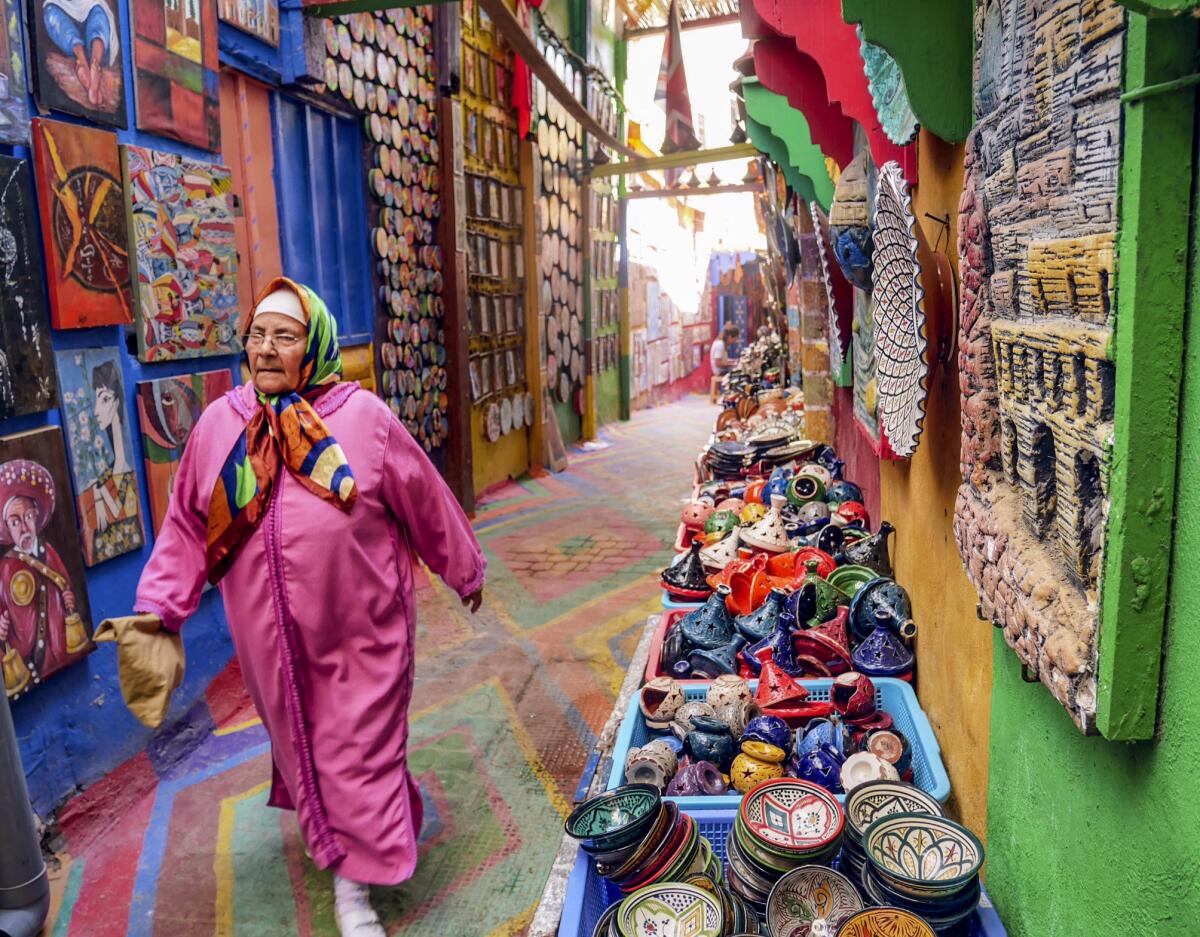 A woman walks down a gaily painted alley in the ancient walled city in Fez.