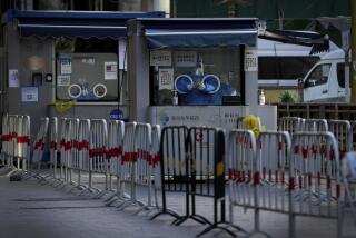 Workers in protective gear wait to administer a COVID-19 test at a quiet coronavirus testing site in Beijing, Sunday, Dec. 11, 2022. Facing a surge in COVID-19 cases, China is setting up more intensive care facilities and trying to strengthen hospitals as Beijing rolls back anti-virus controls that confined millions of people to their homes, crushed economic growth and set off protests. (AP Photo/Andy Wong)