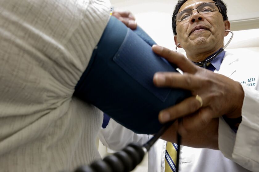 WHITTIER, CA, MAY 26, 2017: Dr. Juan Montes takes the blood pressure of a patient in his Whittier office May 26, 2017. Montes, the son of Santa Paula citrus workers became a doctor, as did his two brothers. He has run 4 medical clinics in the L.A. area for 35-years. In that time, clients have gone from mostly privately insured to mostly Medi-Cal or Medicare (Mark Boster / Los Angeles Times ).