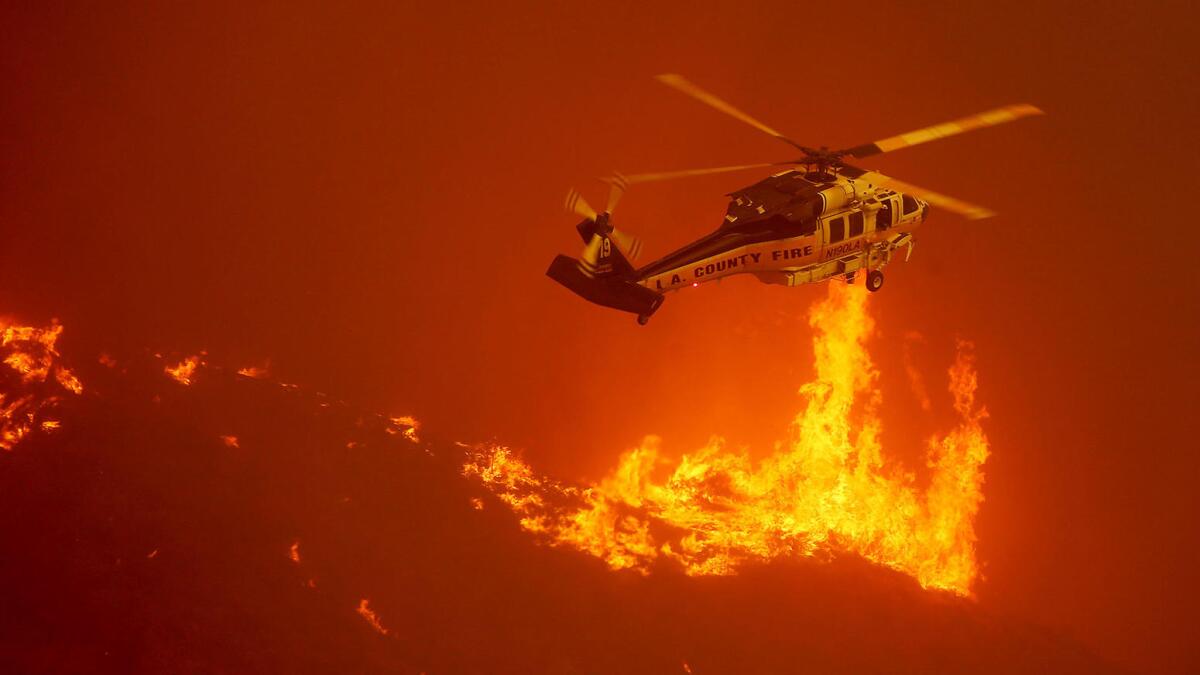 A firefighting helicopter hovers close to the flames from the Sand fire as it burns out of control along Soledad Canyon Road.