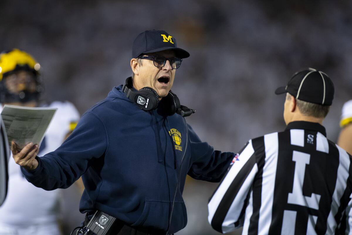 Michigan coach Jim Harbaugh speaks with a line judge during a loss to Penn State on Oct. 19.