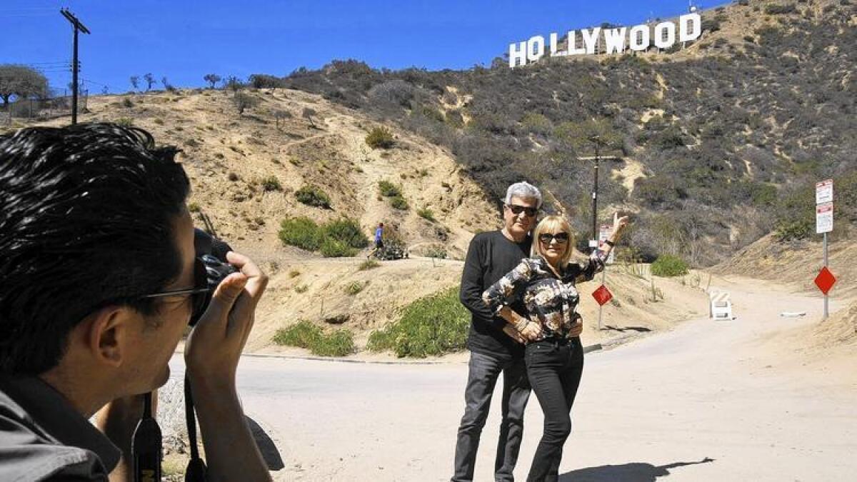 Silvestre Llobet y su esposa, Elena Domenech, visitando desde España, son fotografiados por su hijo, Alejandro Llobet, bajo el letrero gigante de Hollywood. ()