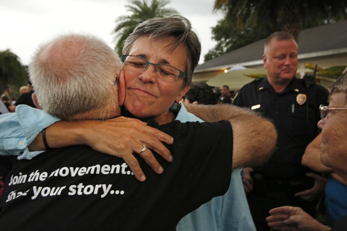 Judy Rettig, center, and Dave Hack, left, hug after a prayer service held at the Joy Meropolitan Community Church in Orlando.