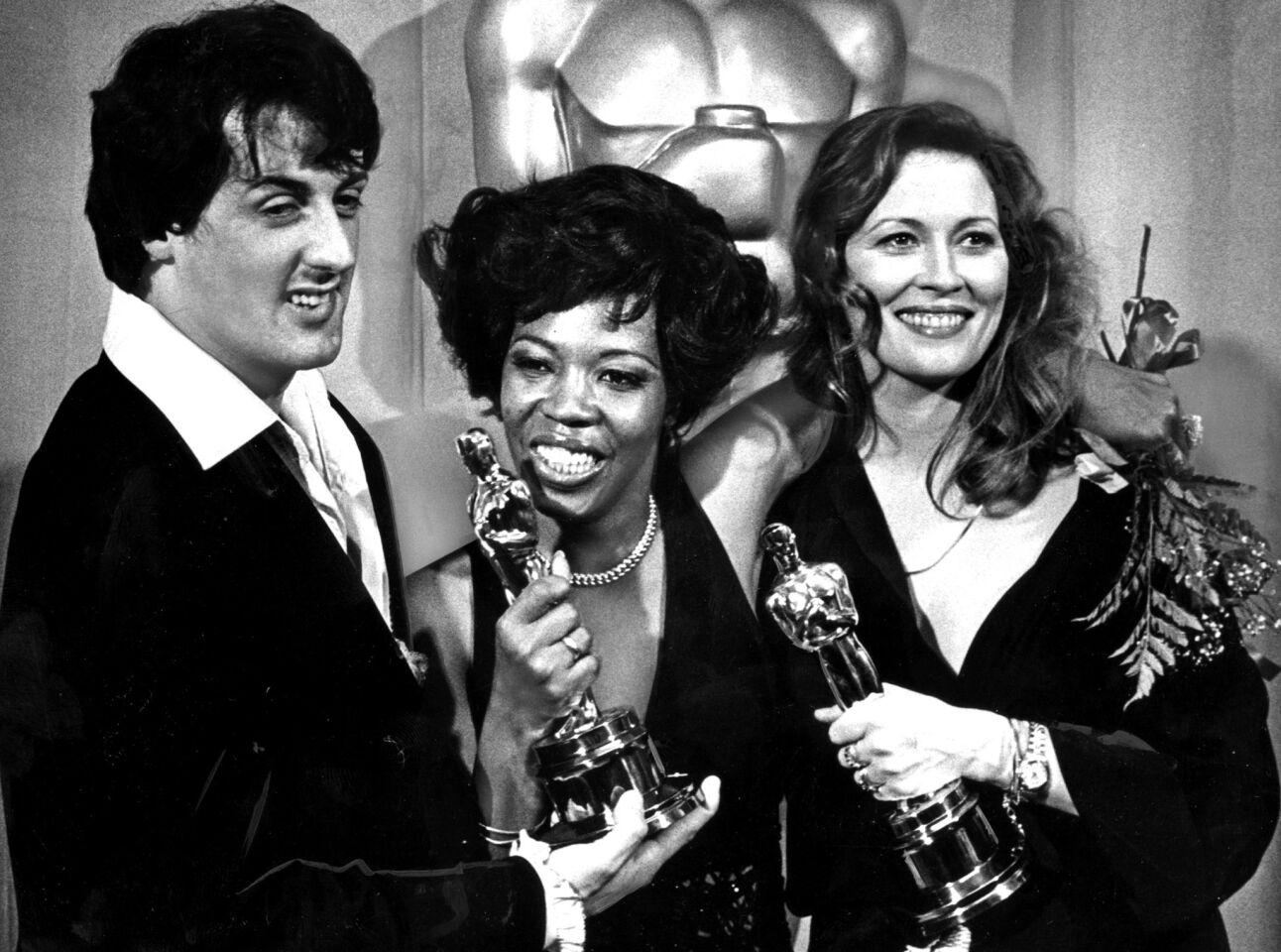 Writer-actor Sylvester Stallone, star of the Oscar-winning film "Rocky," congratulates Peter Finch's widow, Eletha, center, after Finch was posthumously awarded the lead actor award at the 1977 Academy Awards. Faye Dunaway, right, won for lead actress.