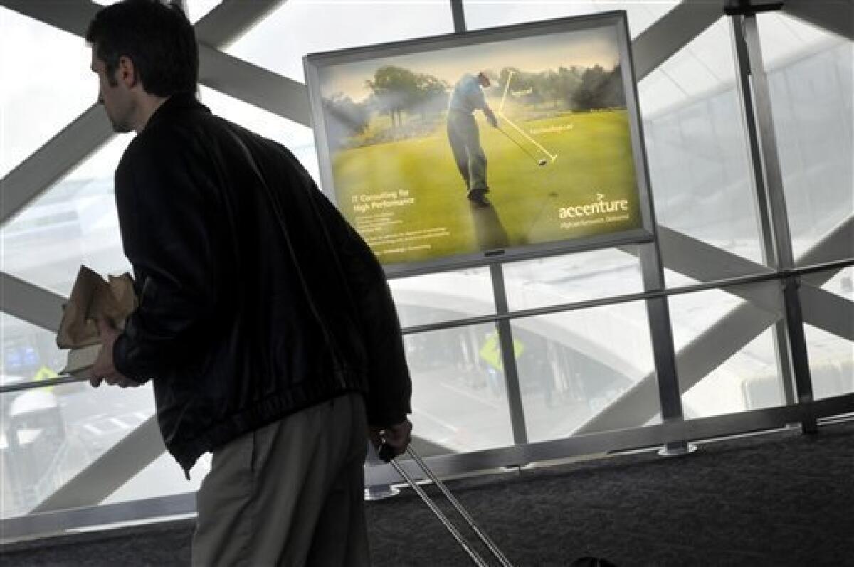 A passenger walks past an Accenture advertisement featuring Tiger Woods at San Francisco International Airport, Monday, Dec. 14, 2009. Accenture, which pinned its entire identity on the golfer, severed its ties with Woods on Sunday, days after he announced an indefinite leave from golf to work on his marriage after allegations of infidelity surfaced in recent weeks. (AP Photo/Russel A. Daniels)