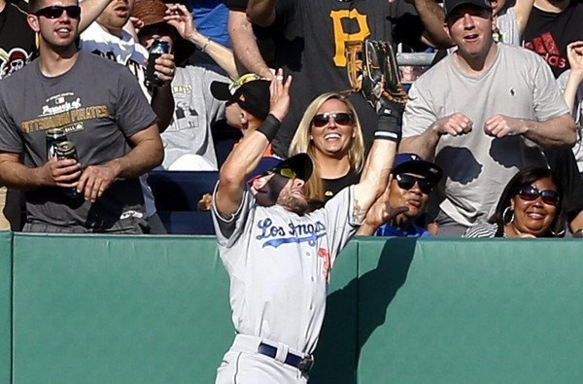 Fans watch as Dodgers left fielder Skip Schumaker makes a leaping catch against the wall on a fly ball hit by Pirates catcher Russell Martin in the sixth inning Saturday.