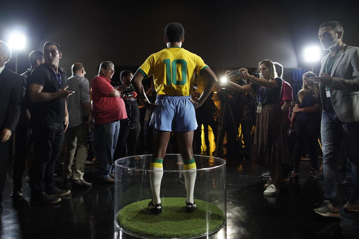 Journalists stand around the statue of legendary Brazilian player Pele at the Brazilian Soccer Team Museum in Rio de Janeiro, Brazil, Thursday, Feb. 20, 2020. The Brazilian Football Confederation unveiled the statue as part of commemorations of 50 years since the World Cup victory in 1970. (AP Photo/Leo Correa)