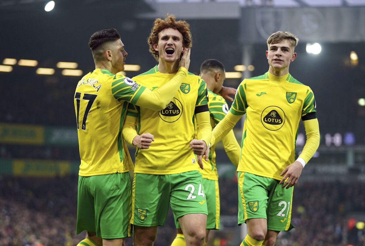 Norwich City's Milot Rashica, Josh Sargent and Brandon Williams celebrate an own goal by Everton's Michael Keane, during the English Premier League soccer match between Norwich City and Everton, at Carrow Road, in Norwich, England, Saturday, Jan.15, 2022. (Joe Giddens/PA via AP)