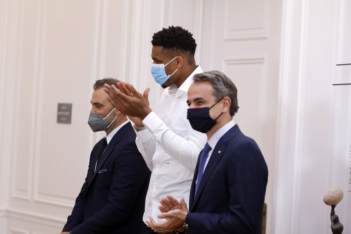Greek Prime Minister Kyriakos Mitsotakis, right, and NBA Champion of the Milwaukee Bucks, who was named NBA Finals Most Valuable Player, forward Giannis Antetokounmpo applaud a naturalization ceremony of his mother Veronica and brother Emeka, at the Maximos Mansion in Athens, Greece, Thursday, Sept. 16, 2021. (Costas Baltas/Pool via AP)