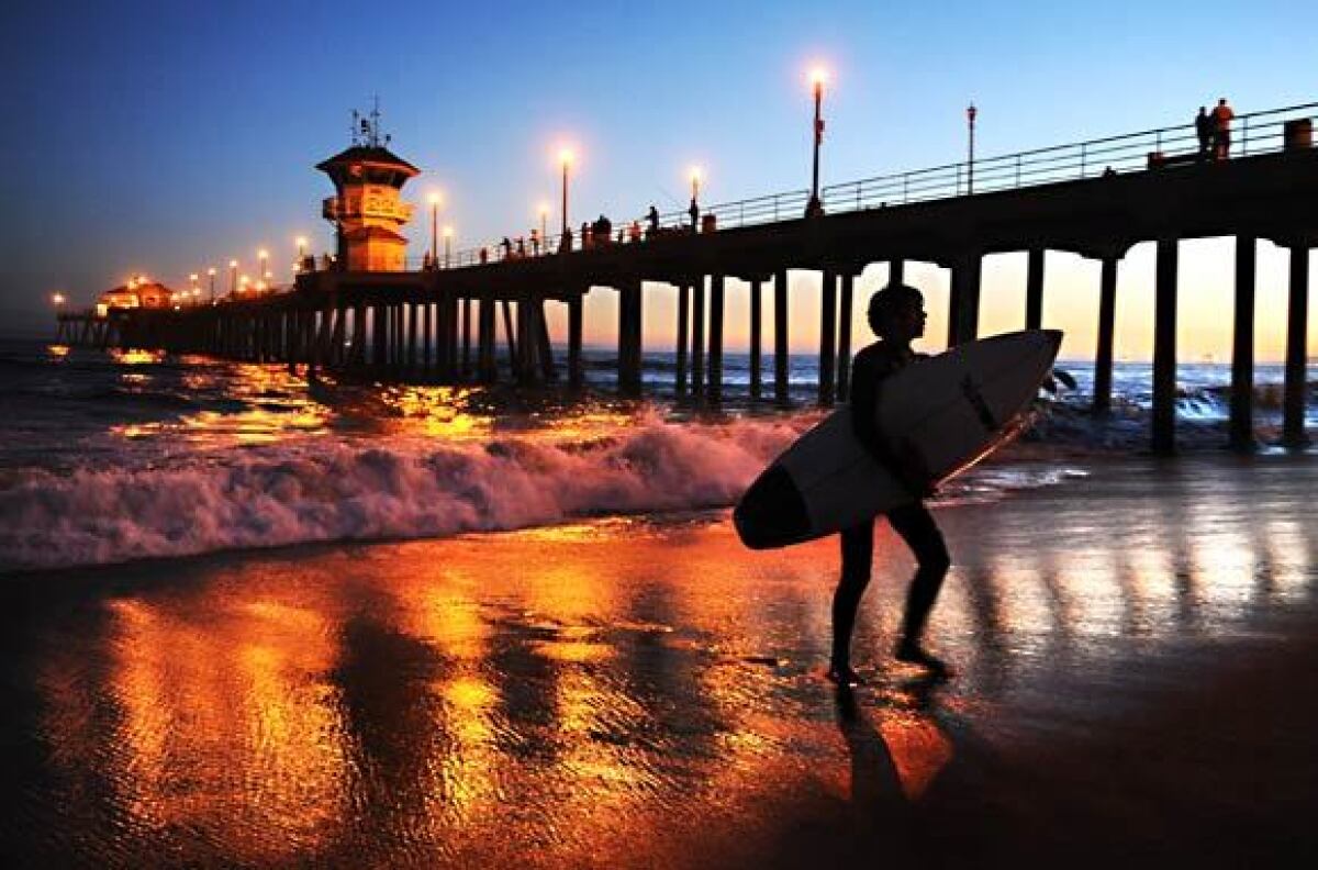 A surfer leaves the water near the Huntington Beach Pier in this file photo. The structure was closed Tuesday as the city works to contain the spread of the coronavirus.