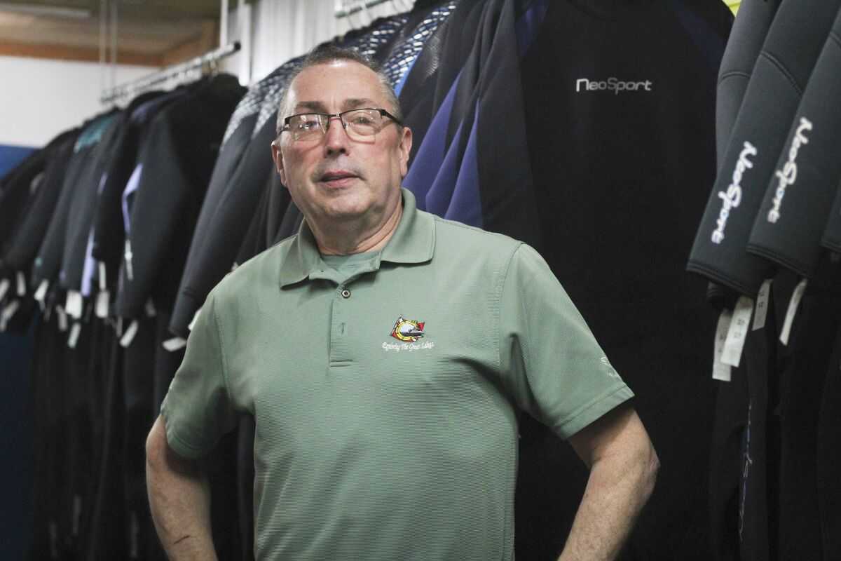 Kevin Stiff owner of The Dive Shop in Flint Township, Mich., stands in his store on Monday, Nov. 9 2021. Stiff wants everyone to know that even though the town where he runs his small business shares a name with the city that became known in recent years for its lead-in-water crisis, they are not the same. The confusion is not isolated to the Flints. As many as 352 of Michigan's 1,240 townships share a name with at least one other township. One name, Grant, is shared by 11 townships. (AP Photo/Anna Liz Nichols)
