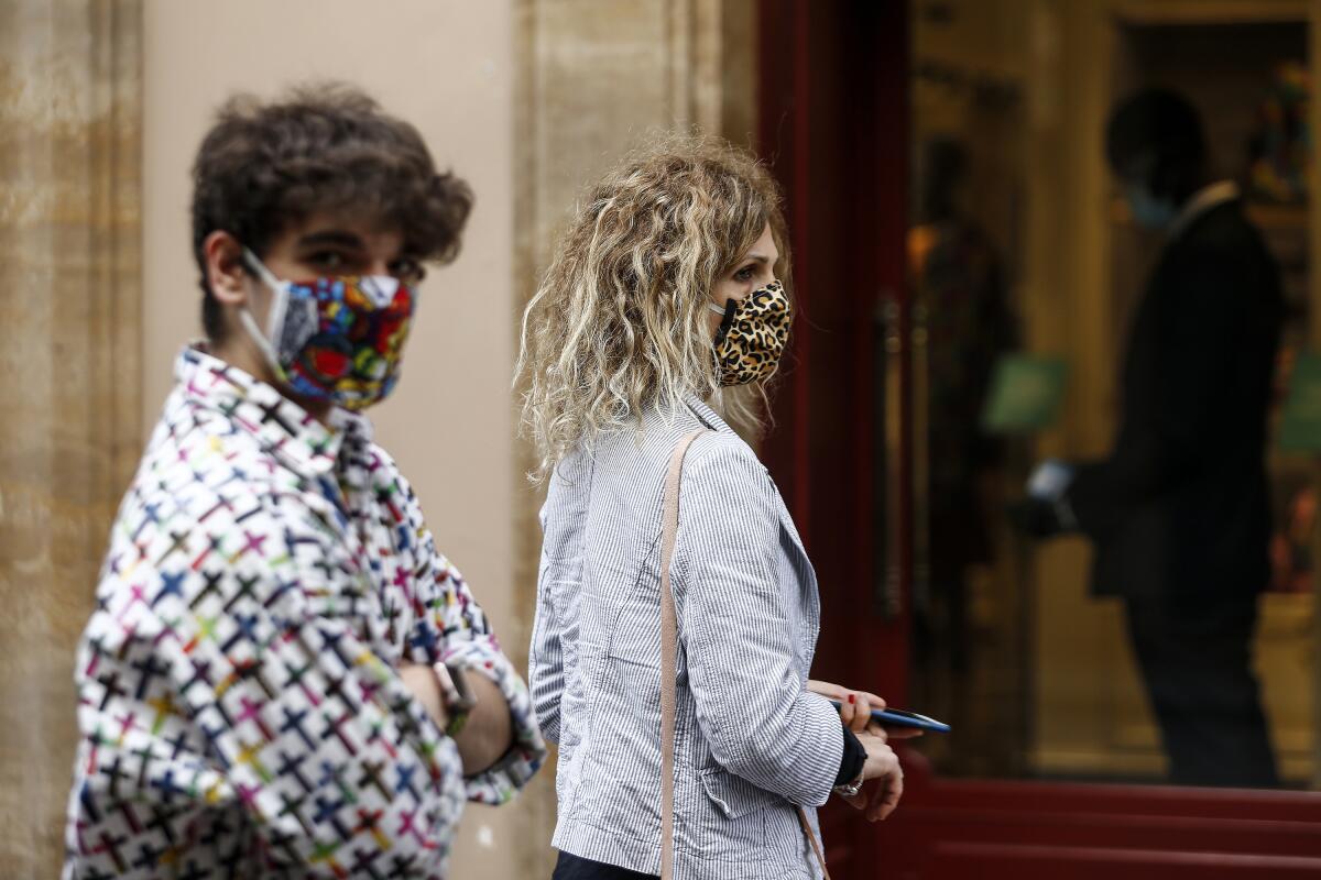 Gente con mascarillas camina por la arteria comercial Via Condotti, de Roma