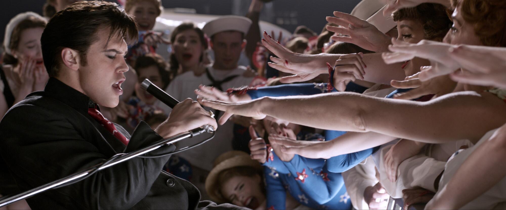 Hands reach out to a singer on stage.