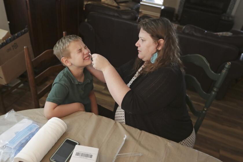Mendy McNulty swabs the nose of her 2-year-old son, Andrew, in their home in Mount Juliet, Tenn. They are part of a nationwide study that aims to answer some of the most vexing mysteries about the coronavirus.