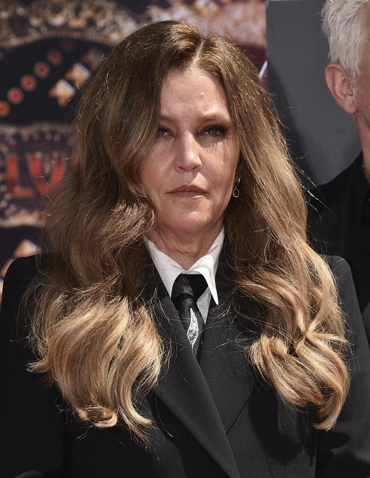 A woman with long brown hair stares forward at an event