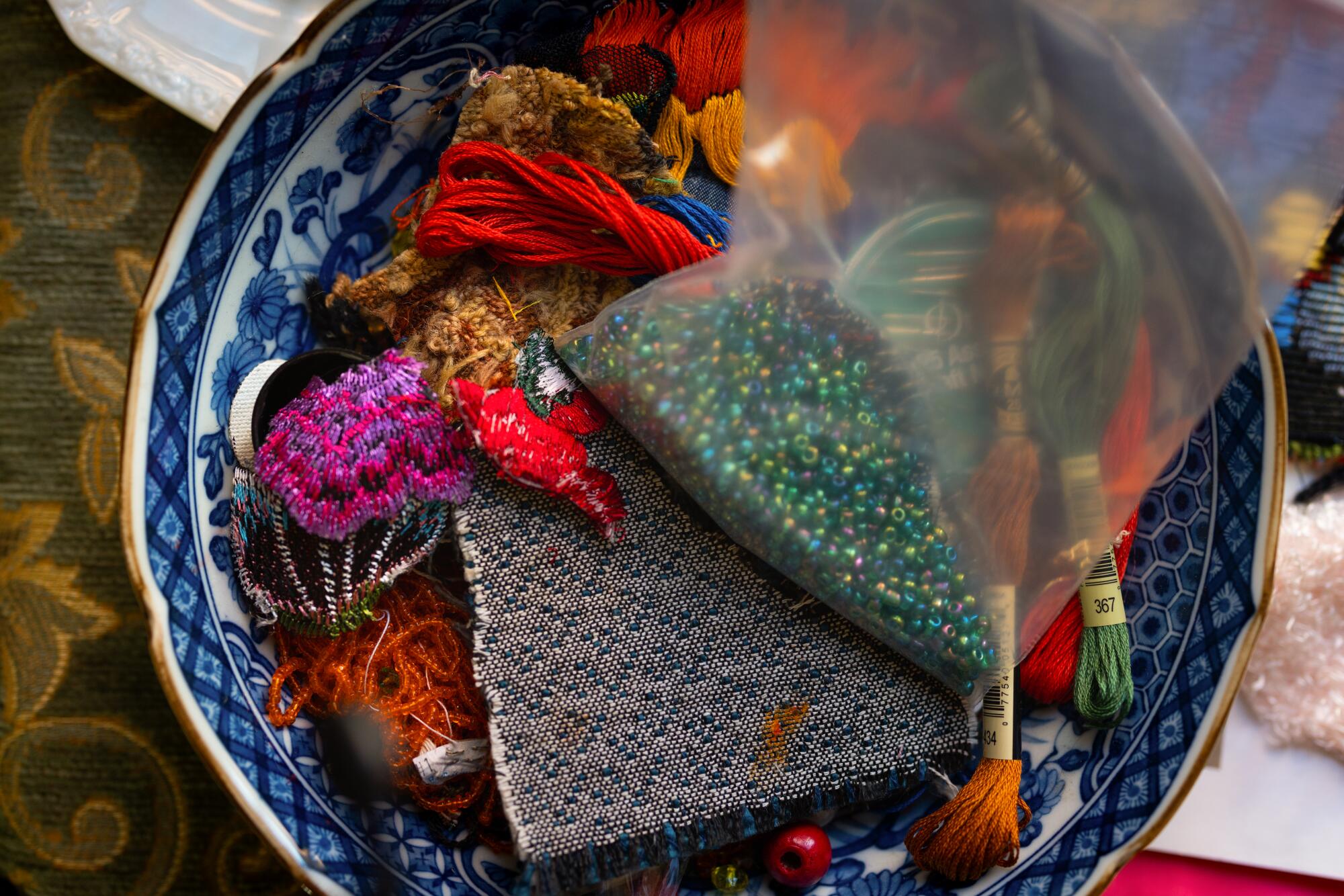 Beads and a variety of threads in a porcelain bowl 